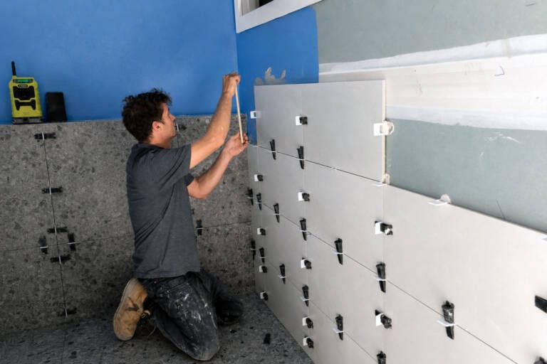 Tiler installing bathroom wall tiles with levelling clips