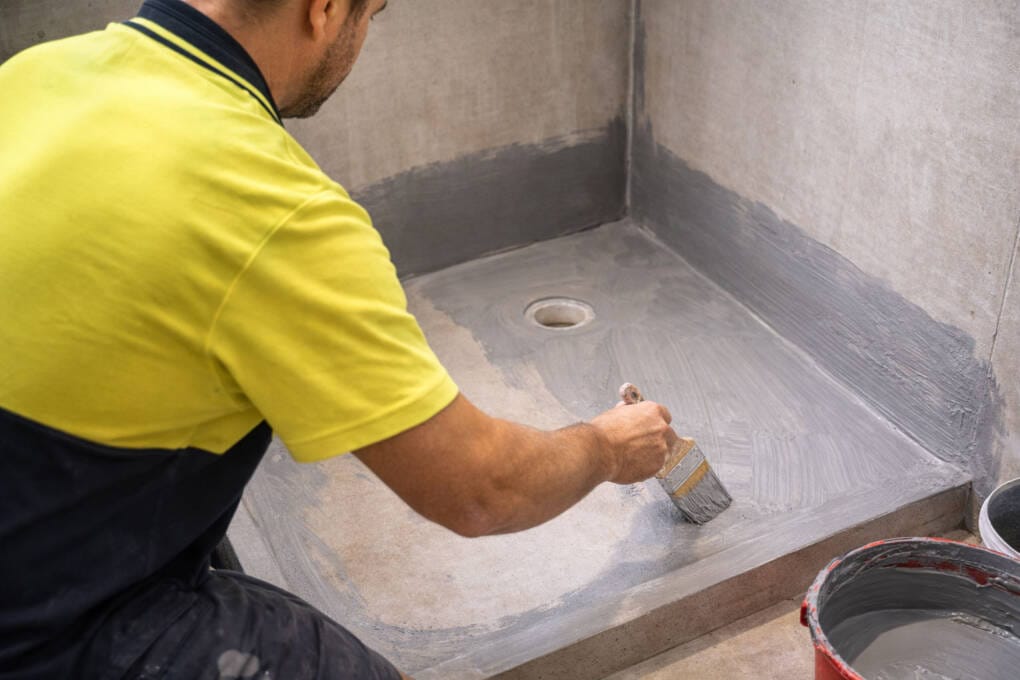 Licensed waterproofer applying membrane to shower recess floor and walls in a Perth bathroom renovation
