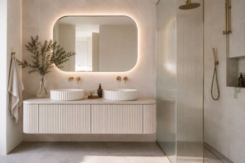 Modern bathroom with reeded vanity front, fluted vessel basins, fluted shower glass and brushed brass tapware