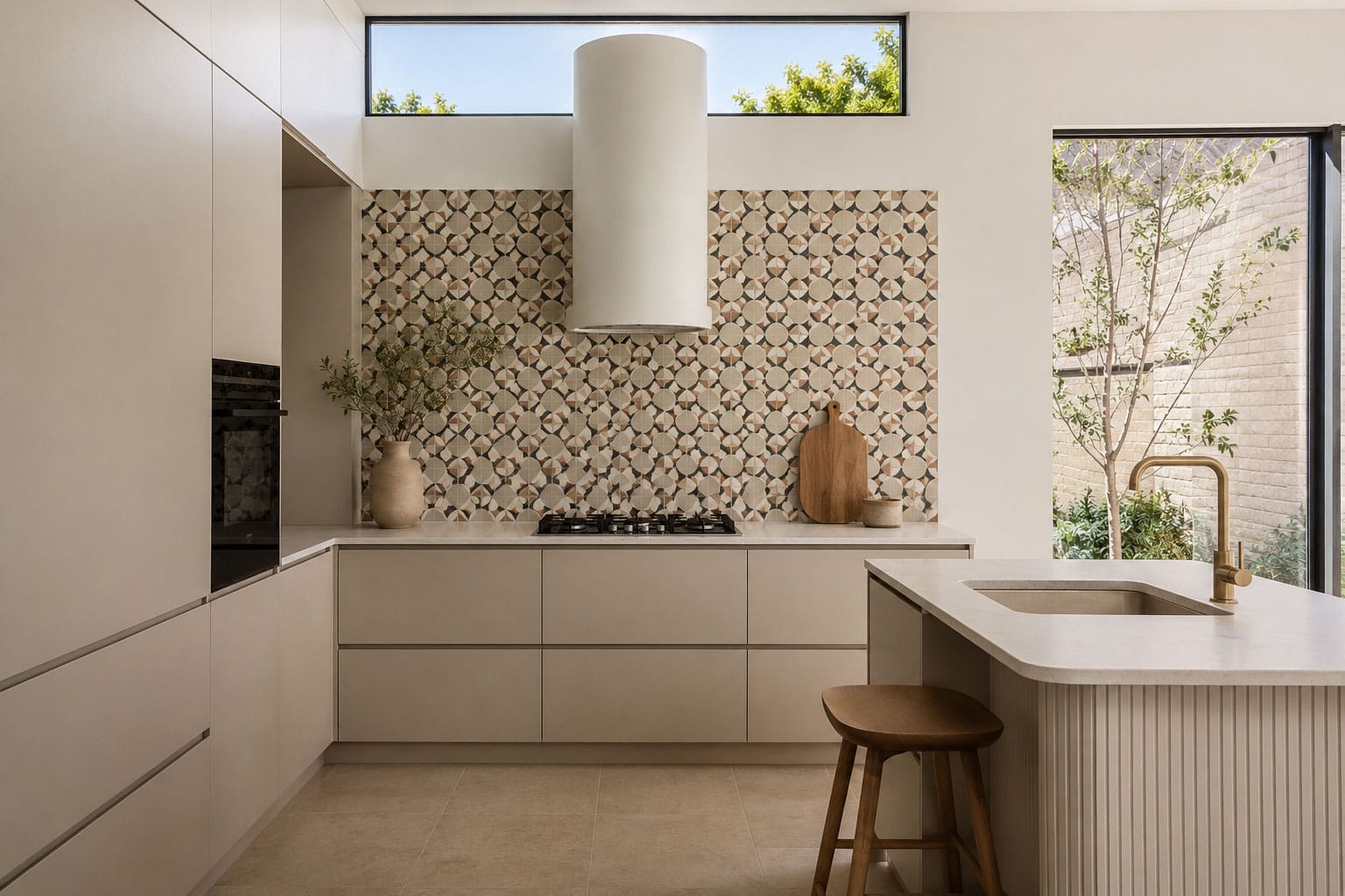 Modern kitchen with a patterned tile splashback feature wall, neutral cabinetry, curved rangehood and warm natural light