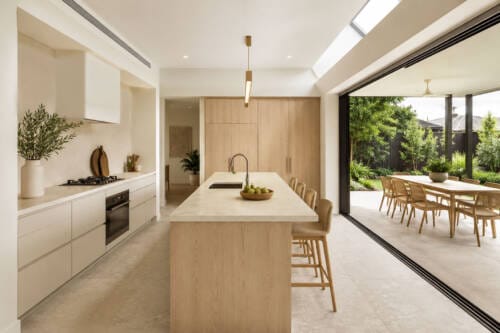 Modern Australian kitchen flowing to an alfresco entertaining area through large sliding glass doors