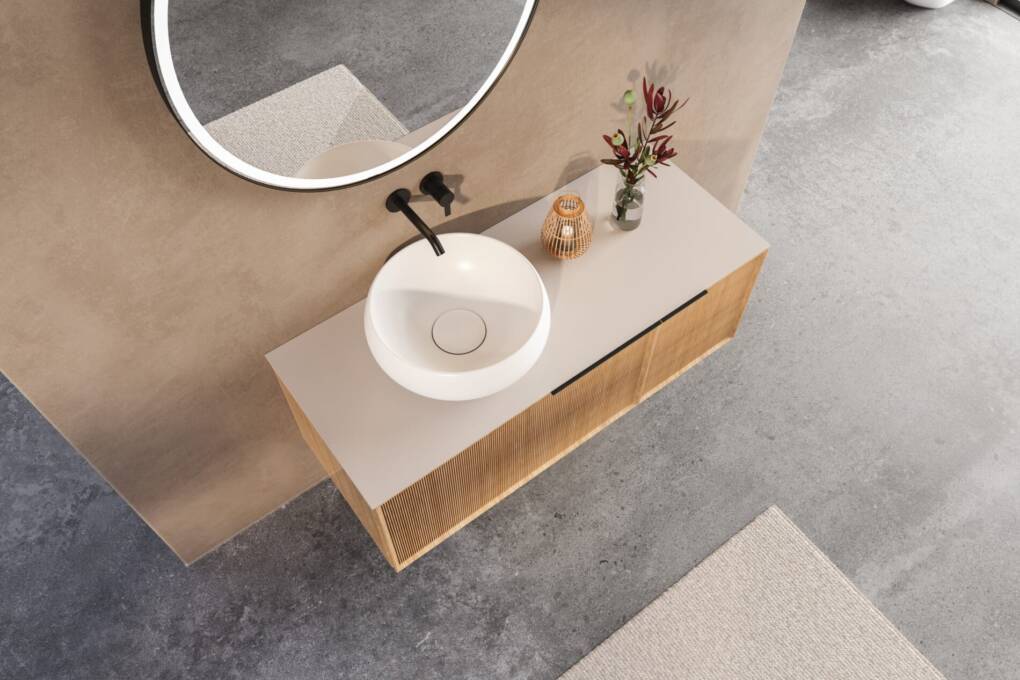 Above counter basin on flat vanity top with round mirror and modern wall-mounted tap