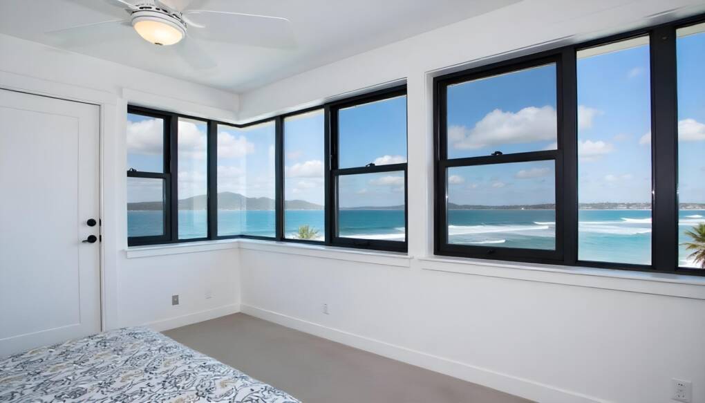 Modern bedroom with black frame double hung windows and ocean view