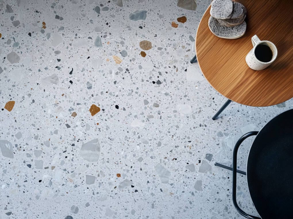 terrazzo tile floor with round wooden table coffee cup and plates overhead view