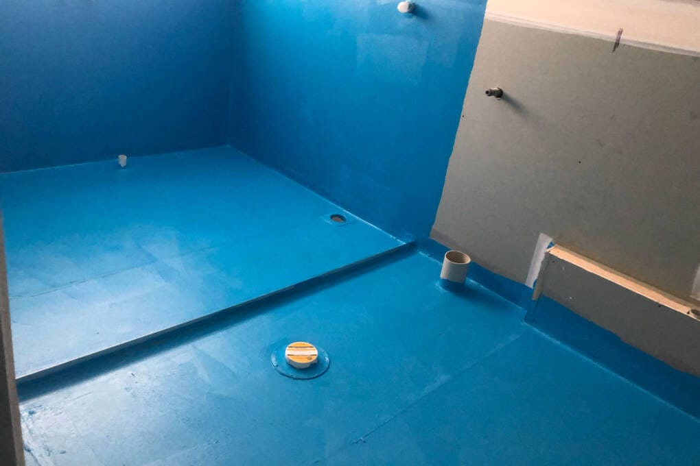 Bathroom waterproofing membrane applied to floor and shower area before tiling