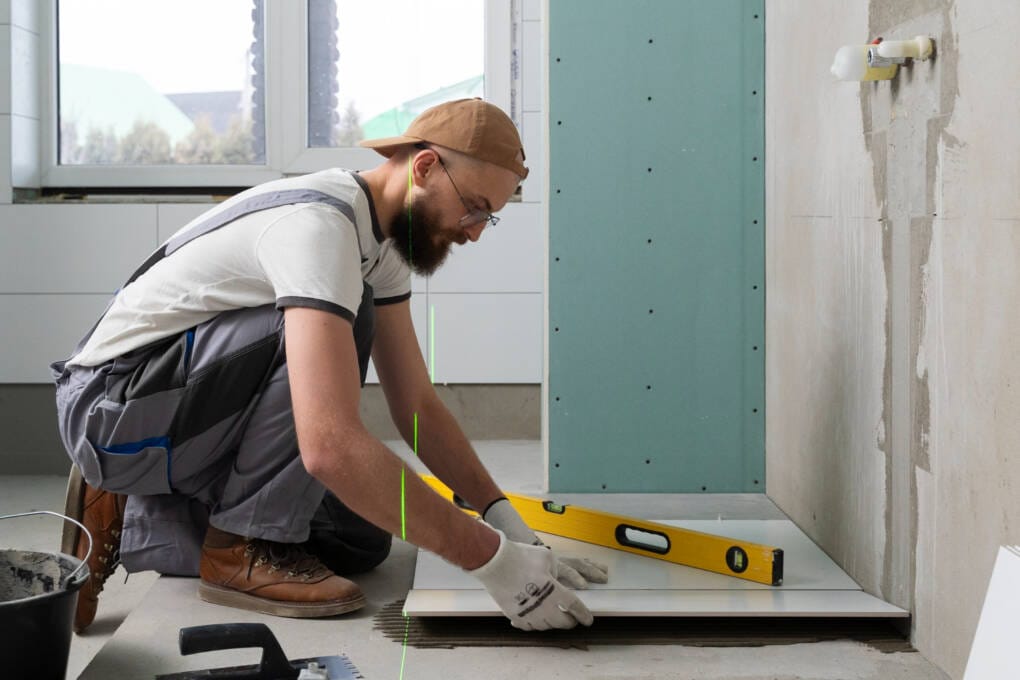 Professional tiler installing large format bathroom floor tiles using levelling spacers