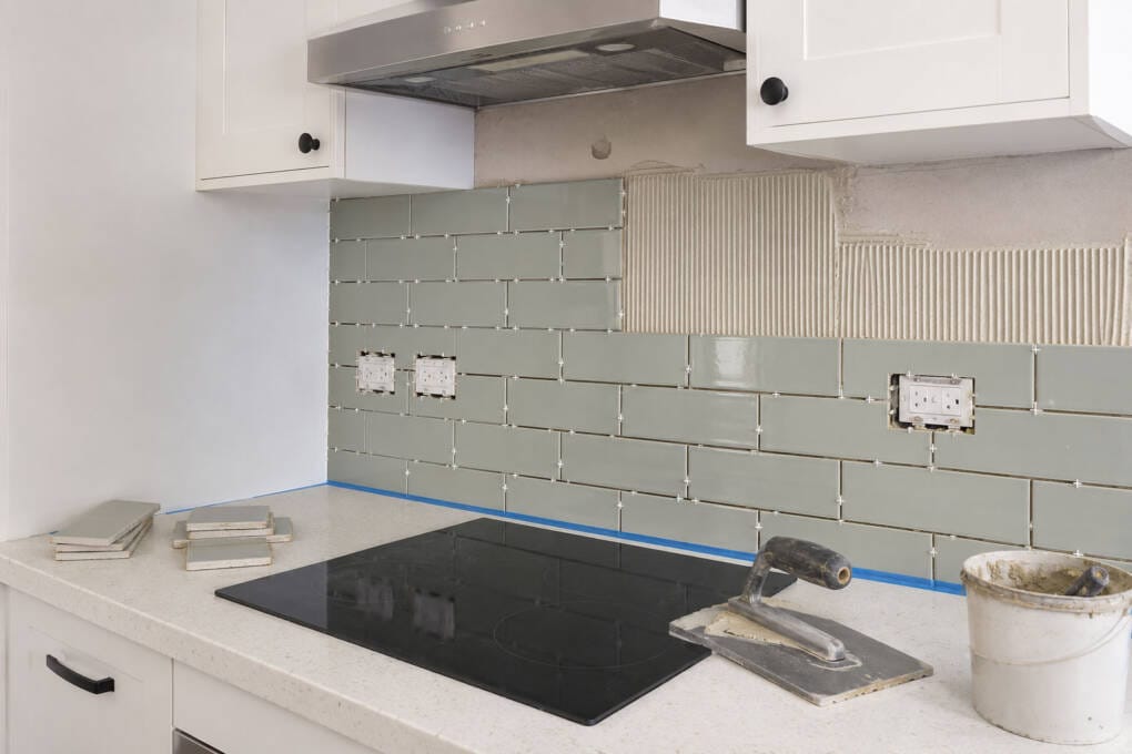 Kitchen splashback installation with subway tiles, power point cut-outs, rangehood area and tile adhesive