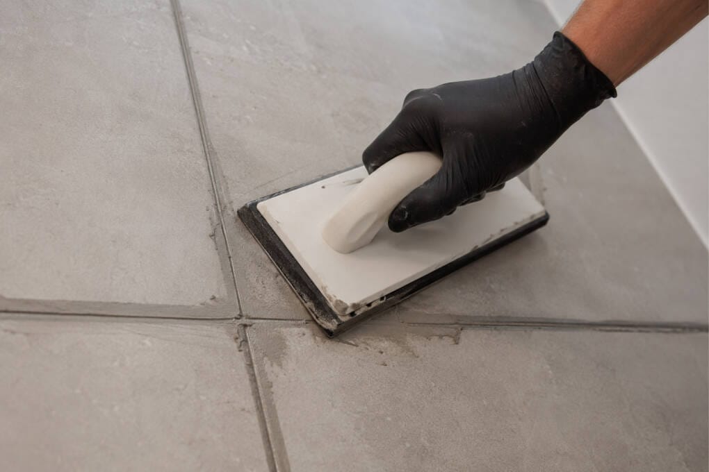 Applying tile grout diagonally across joints with a rubber grout float