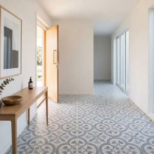 A bright and welcoming home entryway featuring patterned blue and grey ceramic encaustic look floor tiles